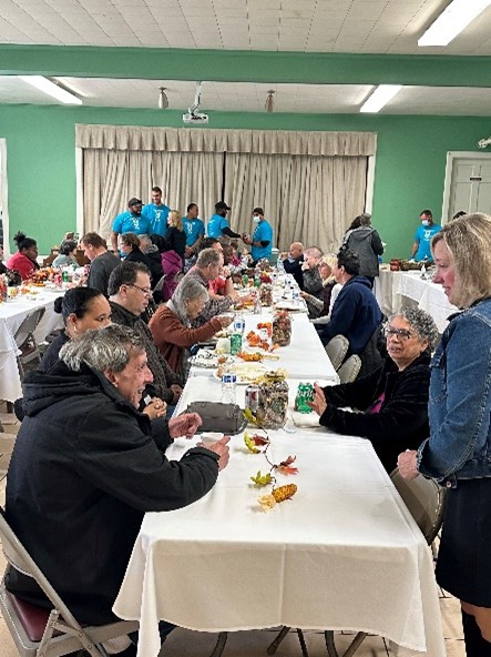 Many people sitting around tables enjoying an early Thanksgiving meal